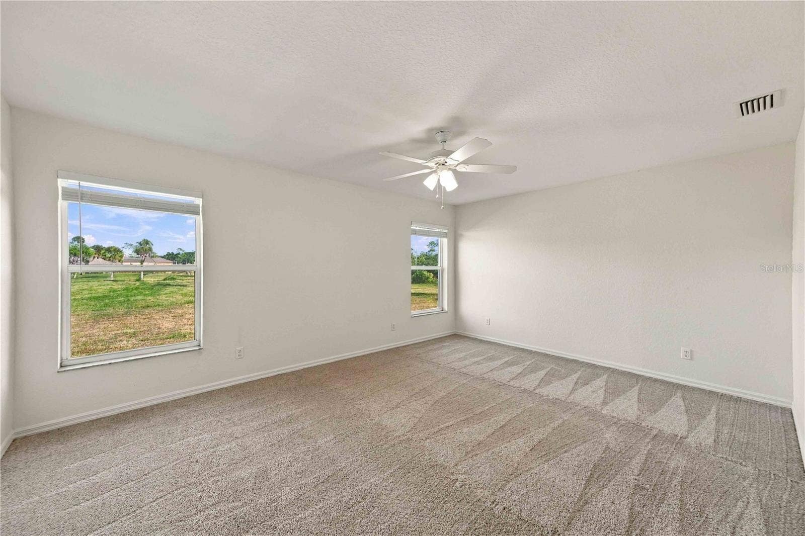 Primary bedroom with ceiling fan and carpet