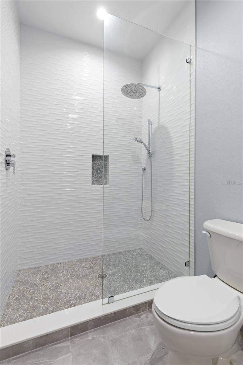 Guest Suite #3 continues with a beautifully updated shower, where wave-textured tile, a rainfall showerhead and handheld fixture bring a little spa-inspired indulgence to your guests stay.