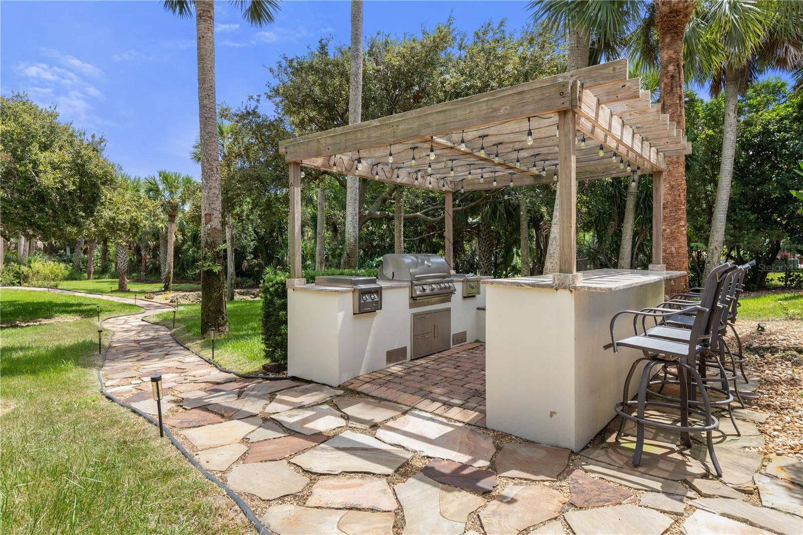 A private culinary retreat beneath the palms, where a beautifully appointed outdoor kitchen transforms alfresco dining into an occasion all its own.