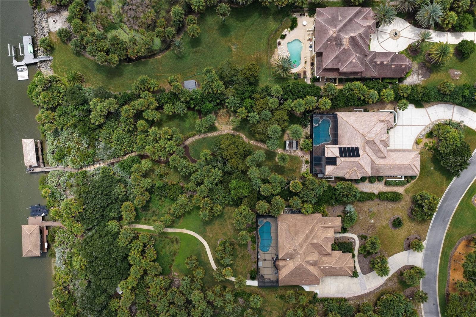 A winding walkway meanders through the lush, park-like grounds, creating a beautiful journey from home to waters edge, where your private covered dock awaits for the next adventure