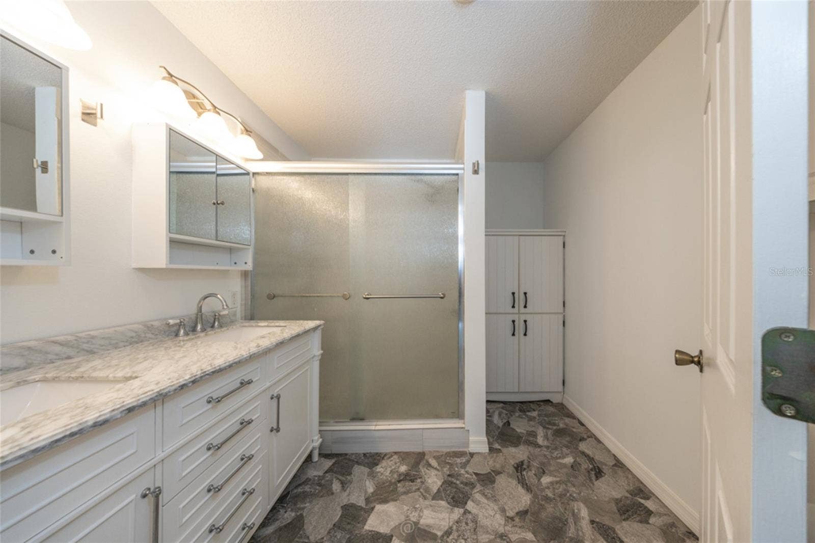 primary bathroom has been updated, including granite countertops, stone floors and large storage cabinet
