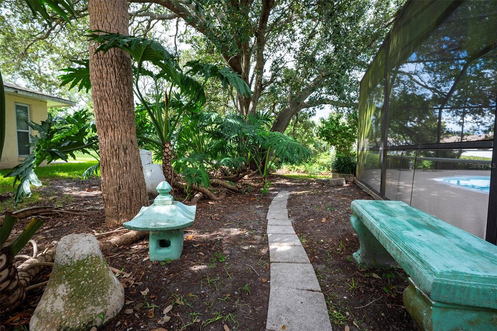 83 FARRAGUT DRIVE, Palm Coast, FL 32137 Small garden area with bench outside the lanai