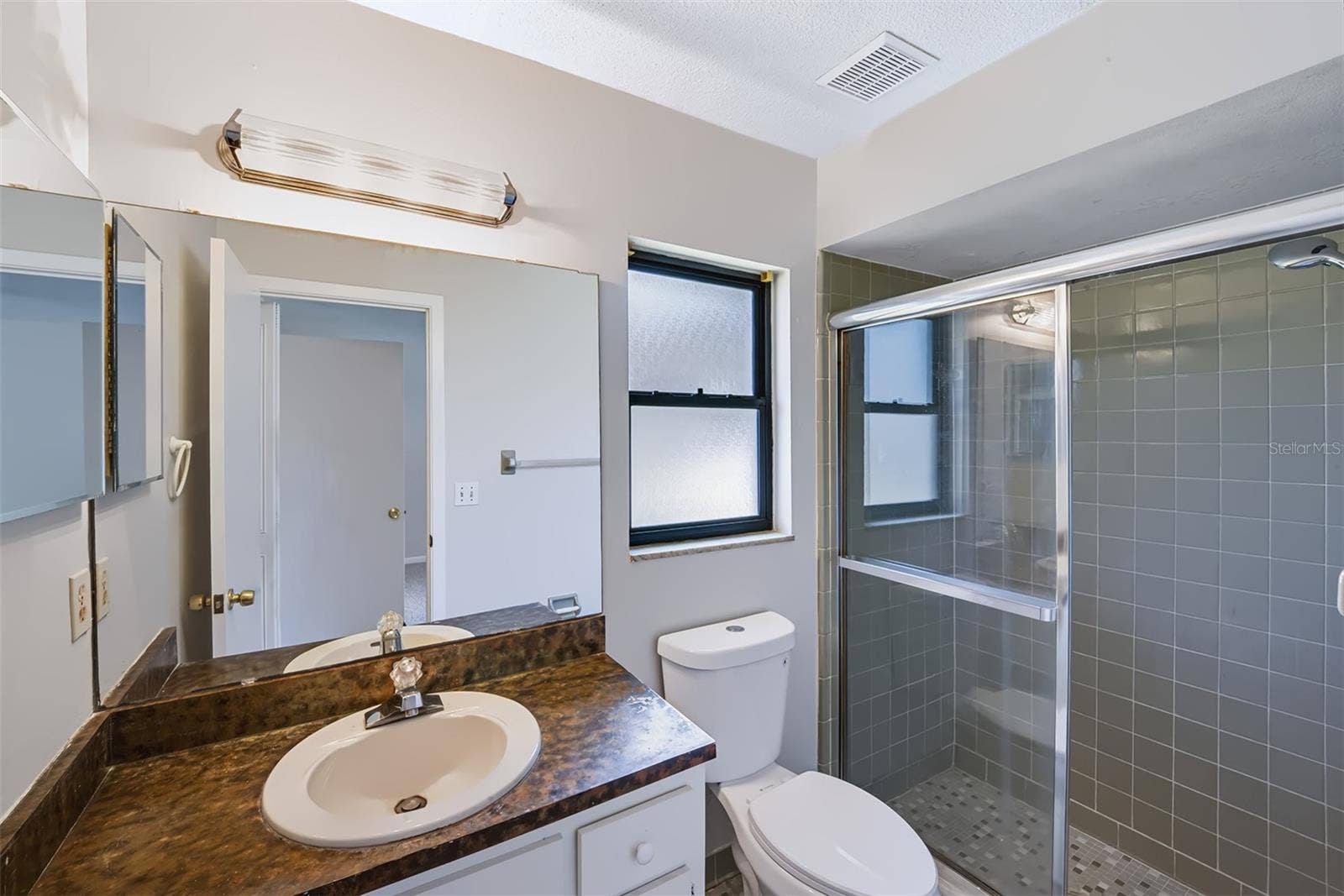 83 FARRAGUT DRIVE, Palm Coast, FL 32137 Master bathroom with shower, built-in medicine cabinet and retro-style glazed ceramic tile throughout