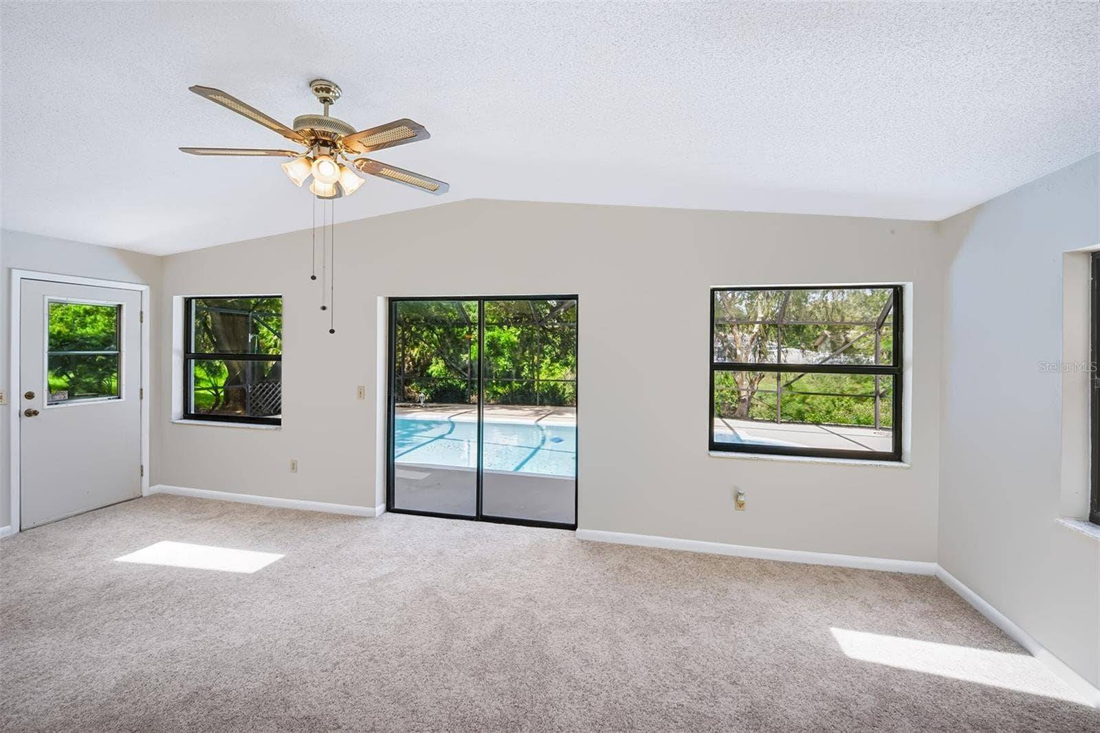 83 FARRAGUT DRIVE, Palm Coast, FL 32137 Florida room with side door and sliding glass doors out to the enclosed lanai/pool area