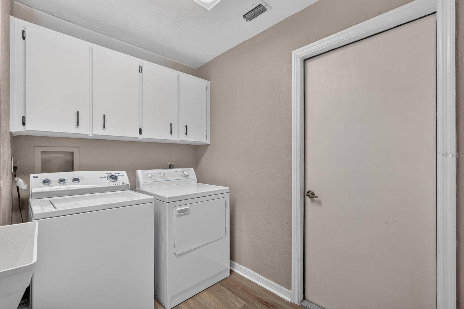 Laundry room has storage cabinetry and utility sink