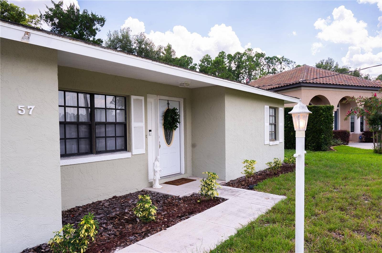 Professional exterior view of the front elevation, showcasing the well-maintained landscaping and inviting entryway.