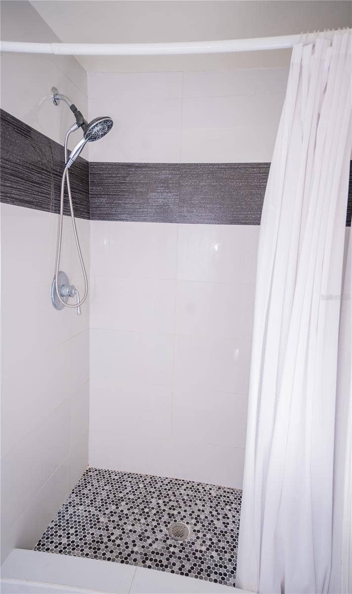 This custom shower features high-end designer tile work, premium fixtures, and luxury tile flooring.