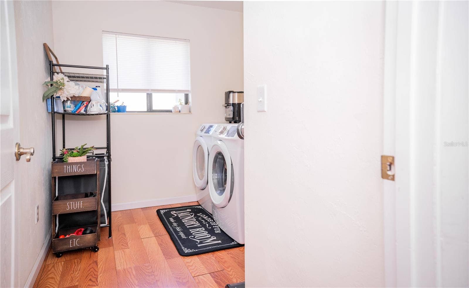 Bright, modern laundry room featuring a full-size washer and dryer with convenient storage space.