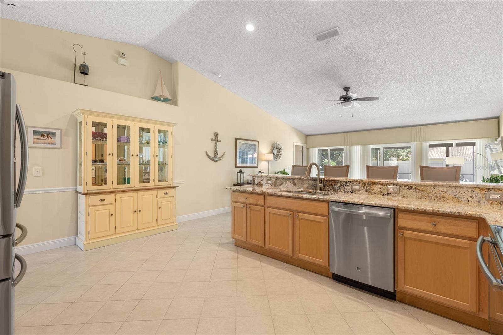 This view showcases the kitchens spacious, open layout, offering plenty of room to move around, while the elevated display shelf above the wall provides a distinctive spot for decorative accents and personal treasures.