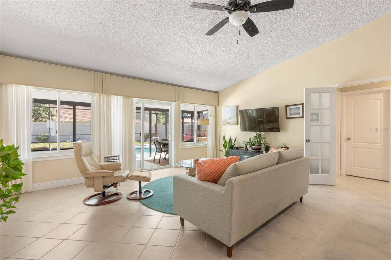 A cozy retreat for movie nights or quiet afternoons, this sunlit living room offers comfortable surroundings, generous windows, and sliding glass doors that lead directly to your poolside escape.