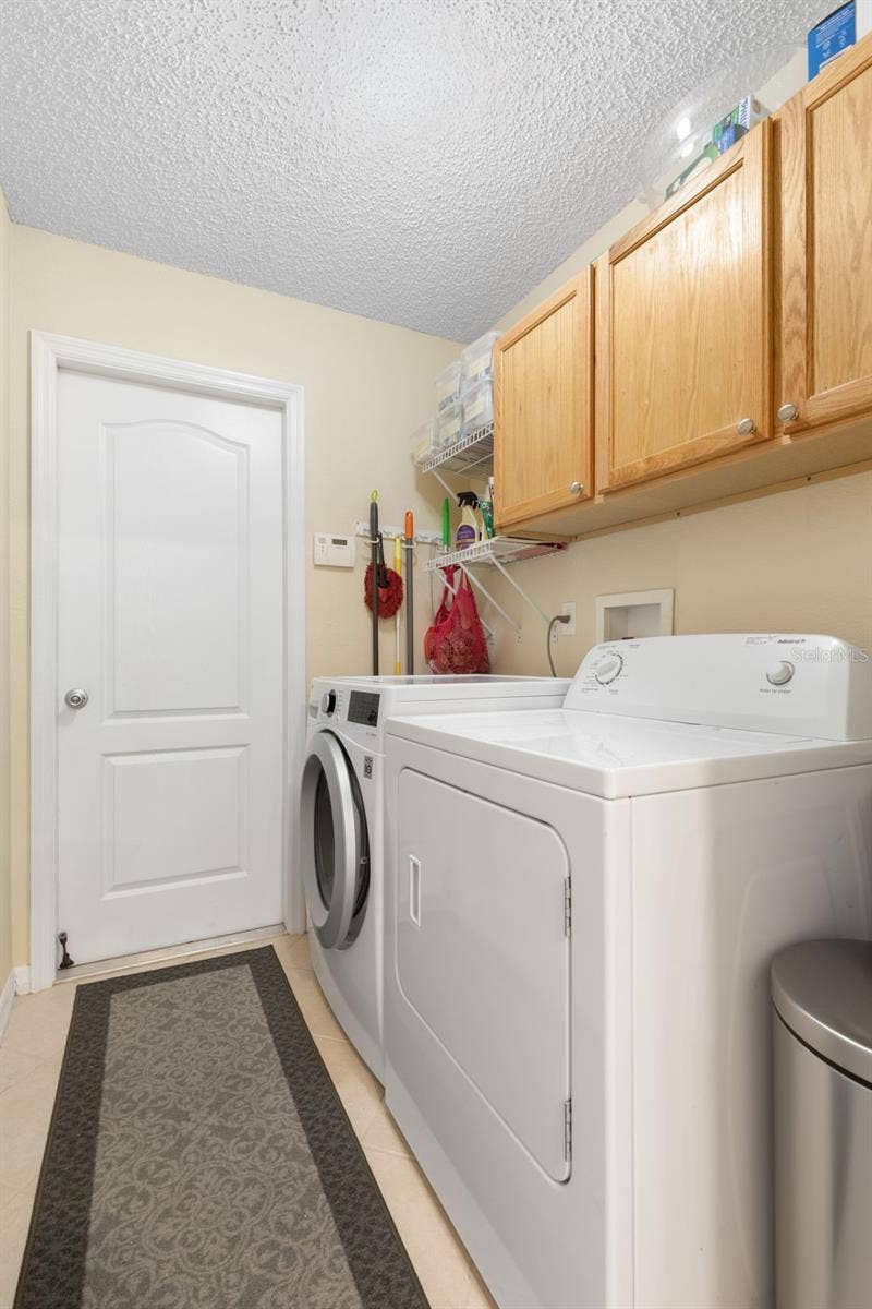 Even laundry day gets a little easier! This dedicated laundry room keeps everything organized with a full-size washer and dryer, overhead cabinetry, and additional shelving for everyday essentials.