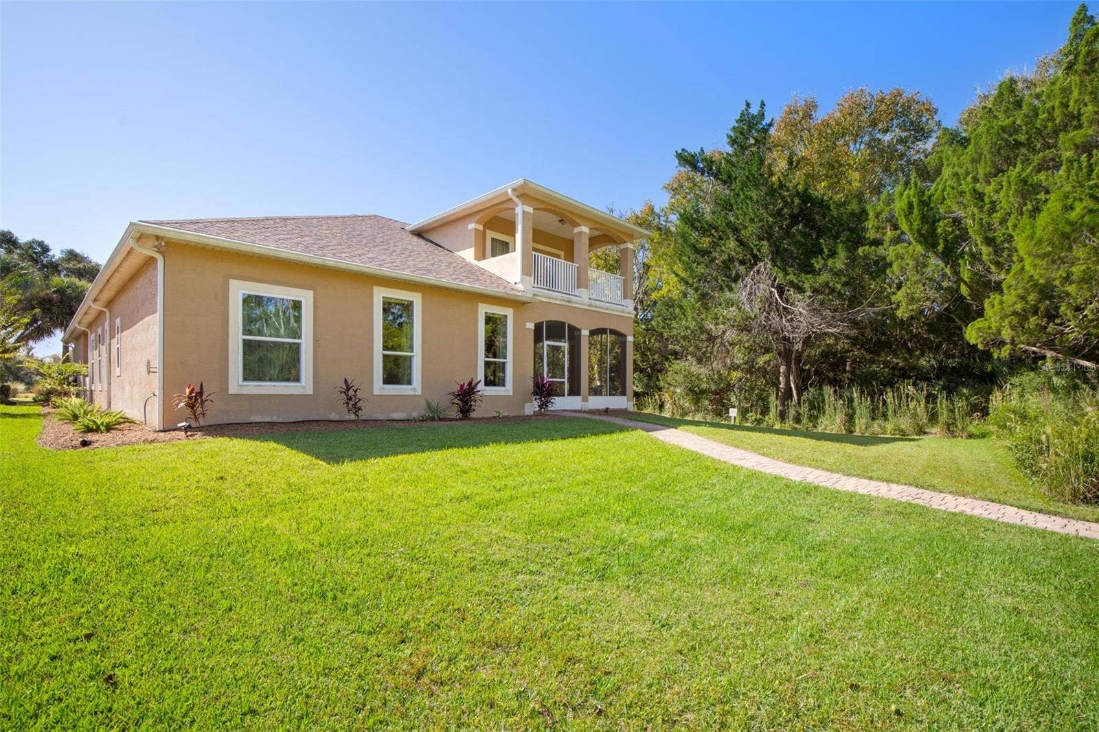 25 EMERALD LAKE COURT, Palm Coast, FL 32137 Rear exterior featuring a private upstairs balcony, screened lanai, and spacious backyard.