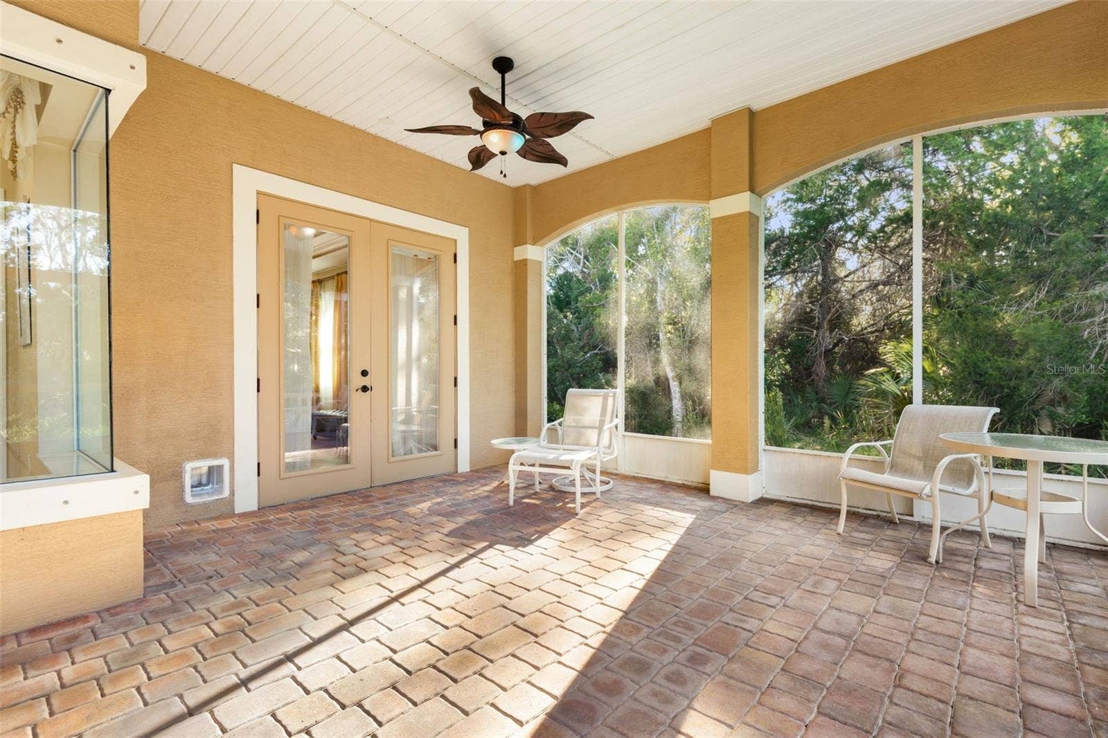 25 EMERALD LAKE COURT, Palm Coast, FL 32137 Screened lanai with paver flooring and French doors leading to the first-floor primary suite.