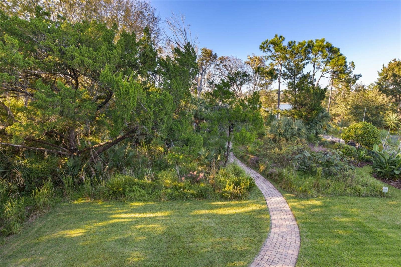 25 EMERALD LAKE COURT, Palm Coast, FL 32137 Winding paver walkway through natural greenery leading toward Emerald Lake.