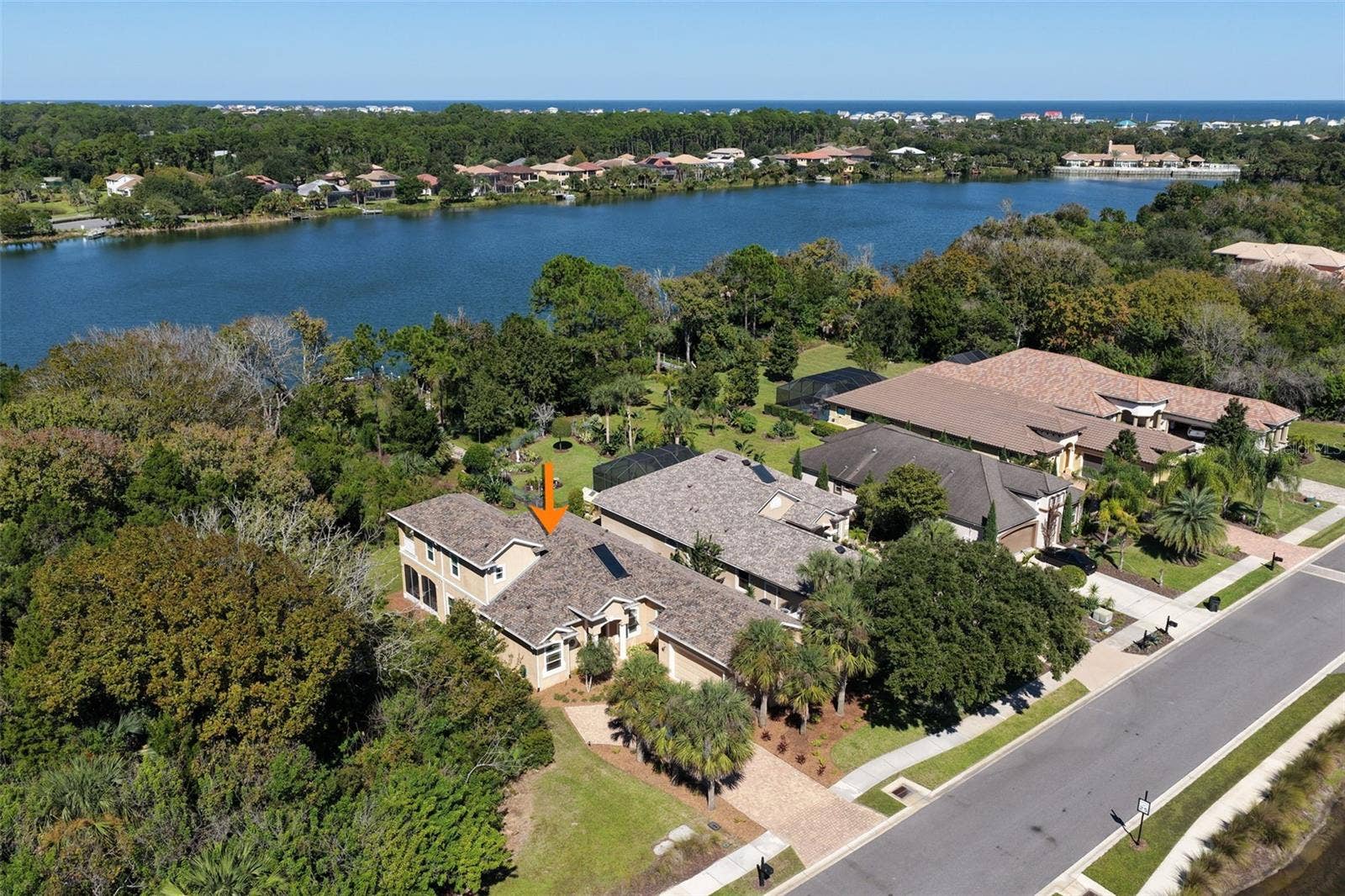 25 EMERALD LAKE COURT, Palm Coast, FL 32137 A sweeping aerial view showcases Emerald Lake behind the property, surrounded by lush natural greenery.