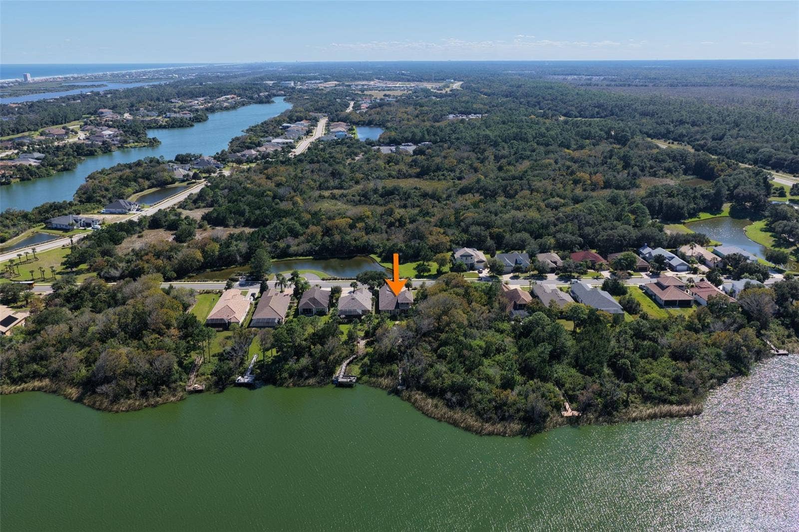 25 EMERALD LAKE COURT, Palm Coast, FL 32137 Aerial perspective showcasing the home's location along Emerald Lake, surrounded by natural greenery within Palm Coast Plantation.