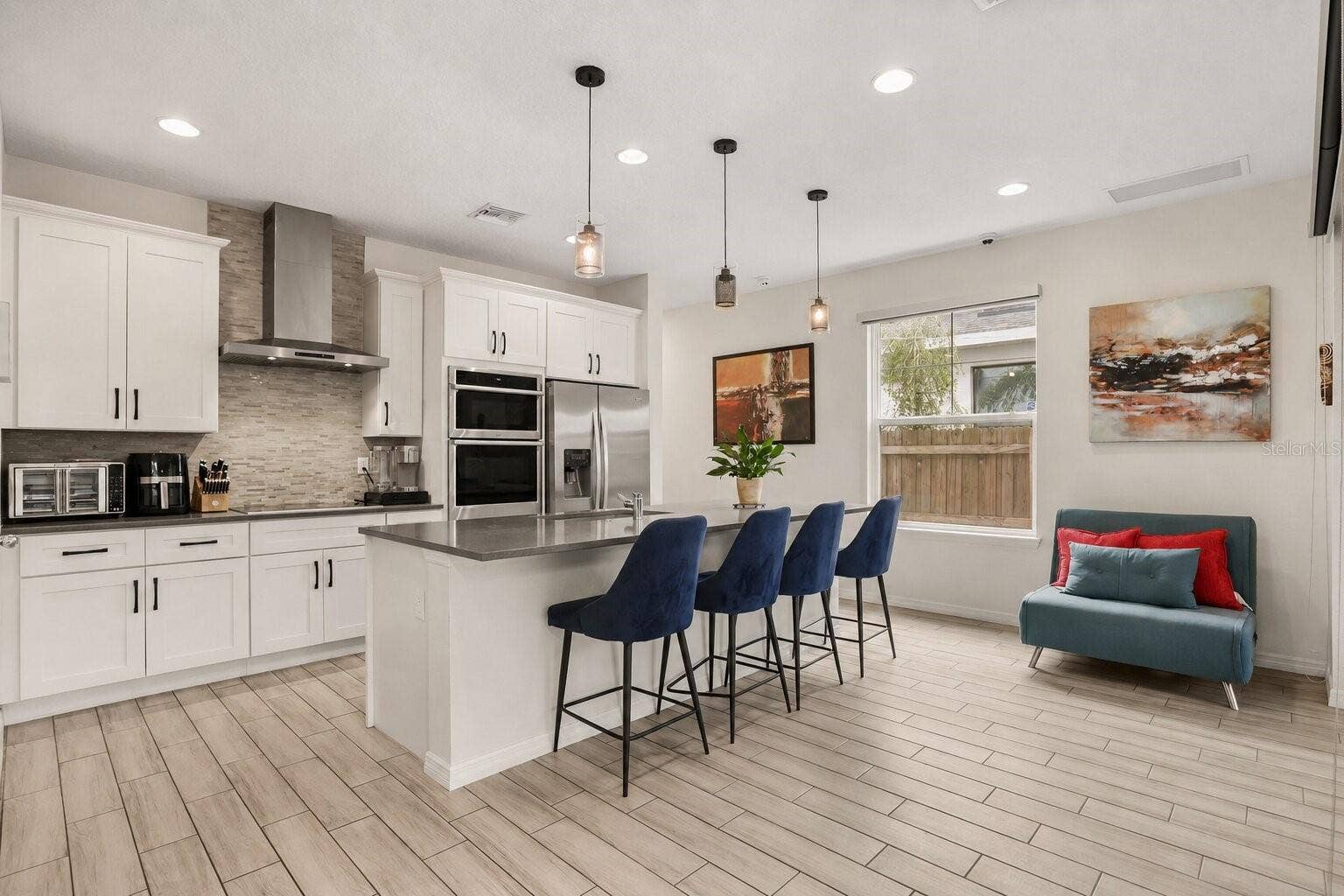 Modern kitchen featuring a large center island with seating, built-in appliances, solid surface countertops, and abundant cabinetry.