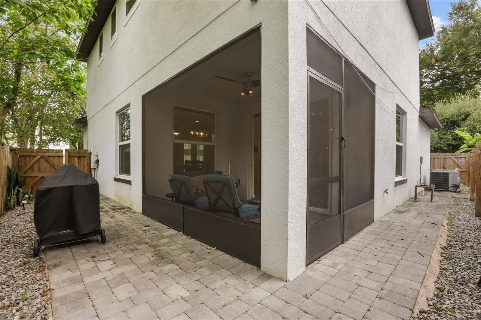 Exterior view showcasing the screened lanai, paver patio, and low-maintenance outdoor living space.