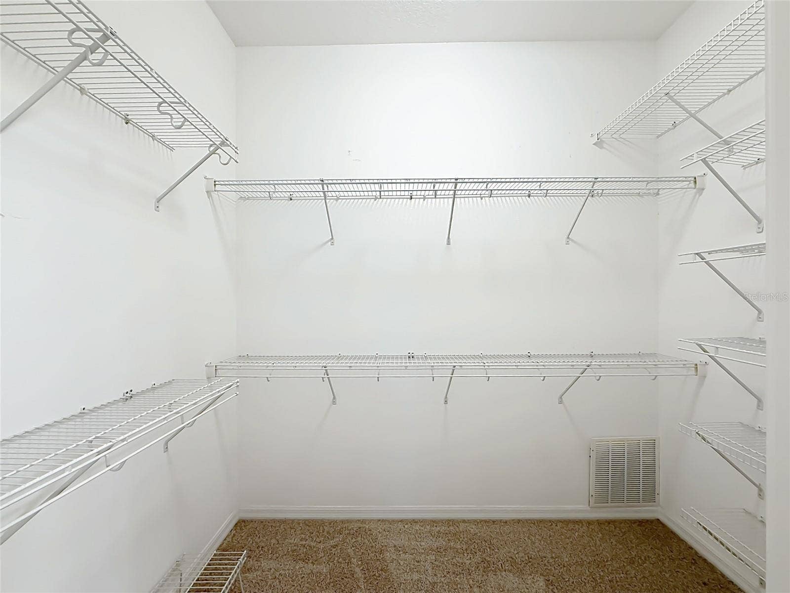 Large Walk in closet with racks and new carpet.