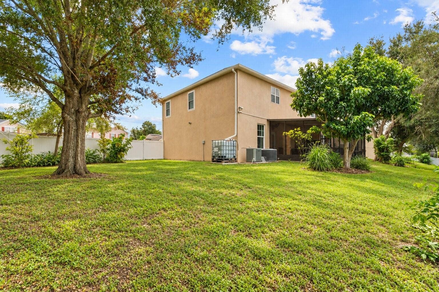 211 HUNT STREET, Clermont, FL 34711 Spacious backyard with mature trees and a screened-in lanai.