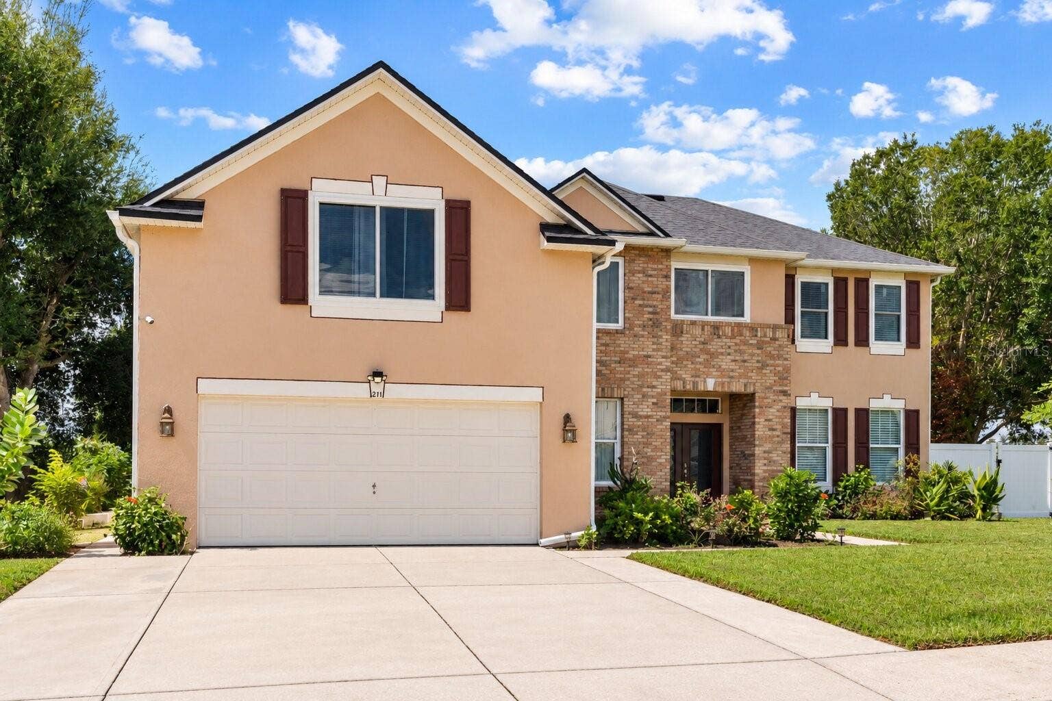 211 HUNT STREET, Clermont, FL 34711 Front exterior featuring the two car garage, landscaped yard, and welcoming curb appeal.