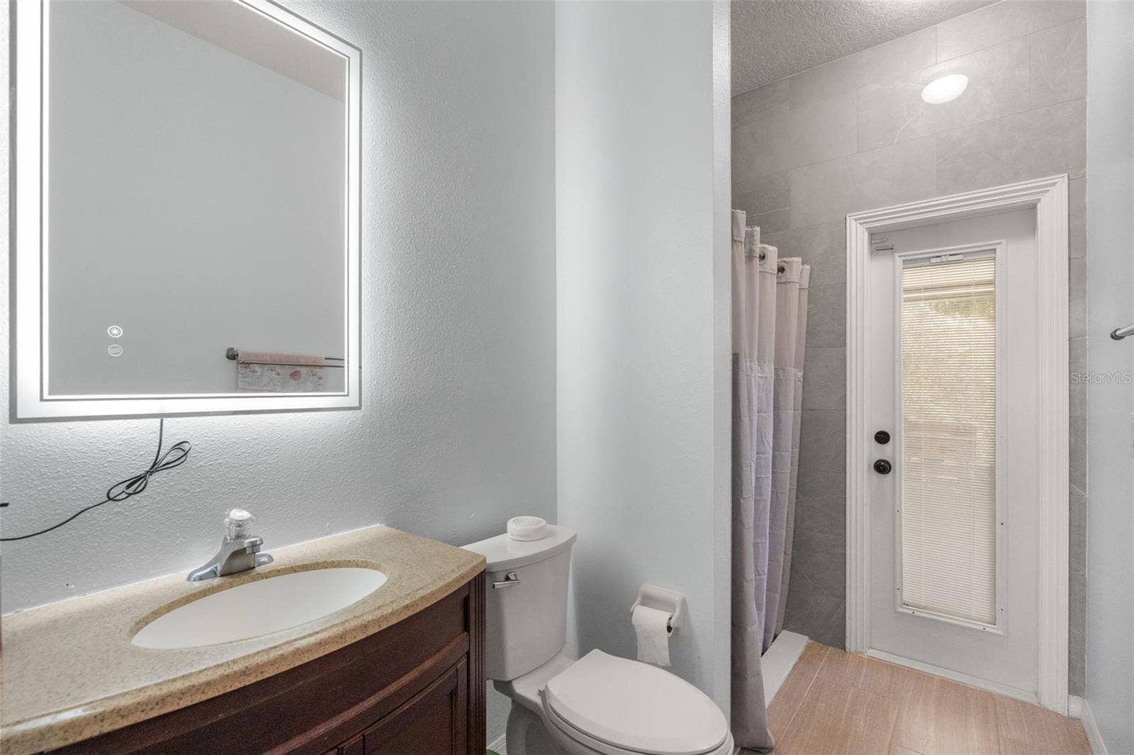 211 HUNT STREET, Clermont, FL 34711 Downstairs bathroom with vanity, mirror, and bright neutral finishes.