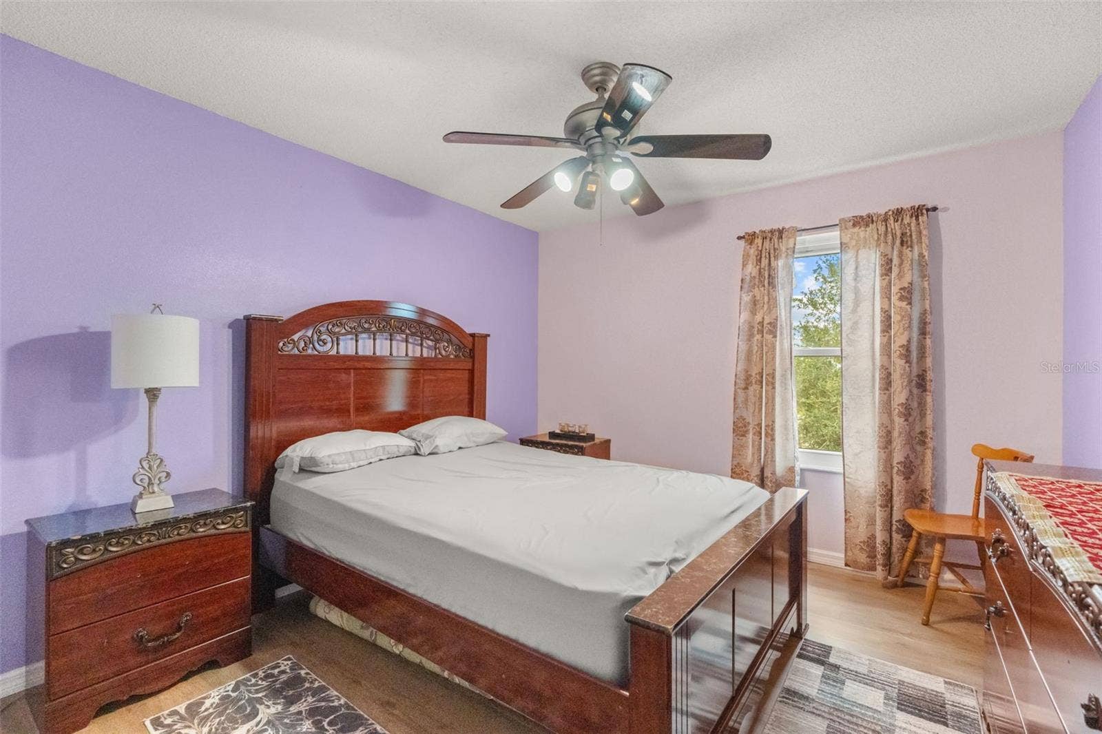 211 HUNT STREET, Clermont, FL 34711 Bright bedroom with ceiling fan, wood-look flooring, and large windows.