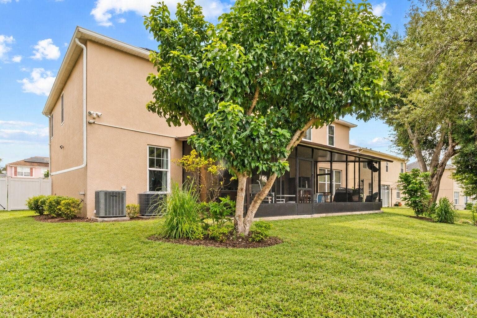 211 HUNT STREET, Clermont, FL 34711 Rear exterior view with a spacious backyard and mature landscaping.