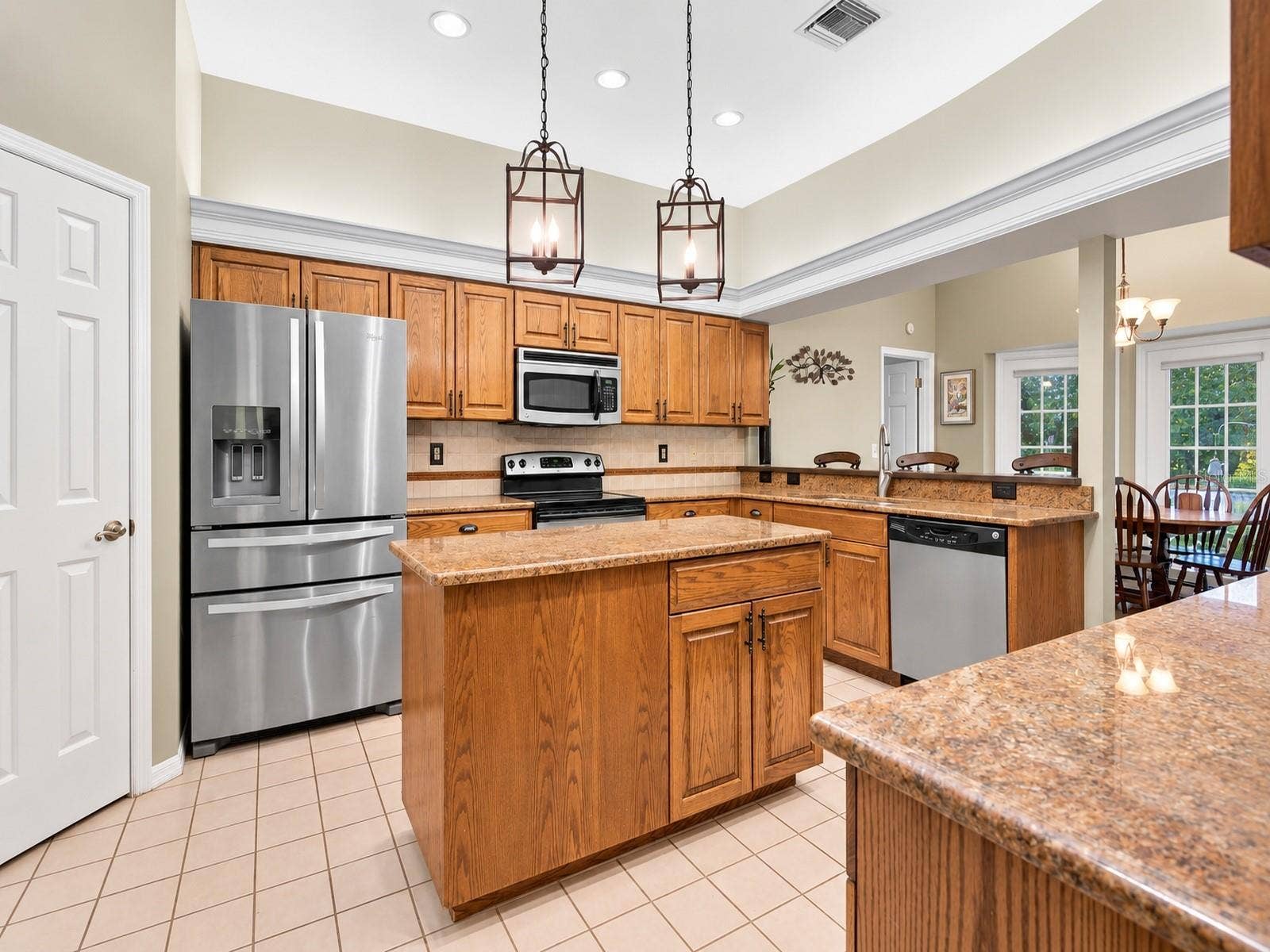 8732 SPRING COURT, Leesburg, FL 34788 Kitchen features oak cabinetry, center island, granite countertops, and stainless steel appliances.