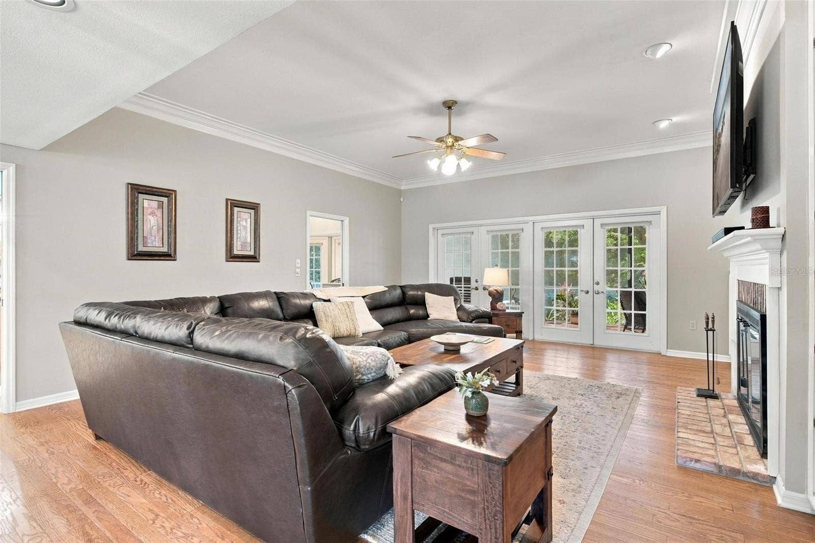 8732 SPRING COURT, Leesburg, FL 34788 Family Room features wood flooring, wood burning fireplace, built in shelving, and French door leading to screened enclosed lanai