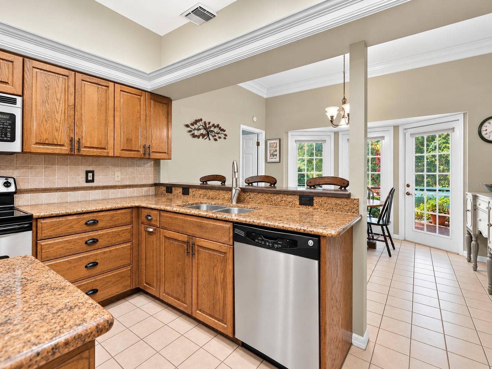 8732 SPRING COURT, Leesburg, FL 34788 Kitchen features oak cabinetry, center island, granite countertops, and stainless steel appliances.