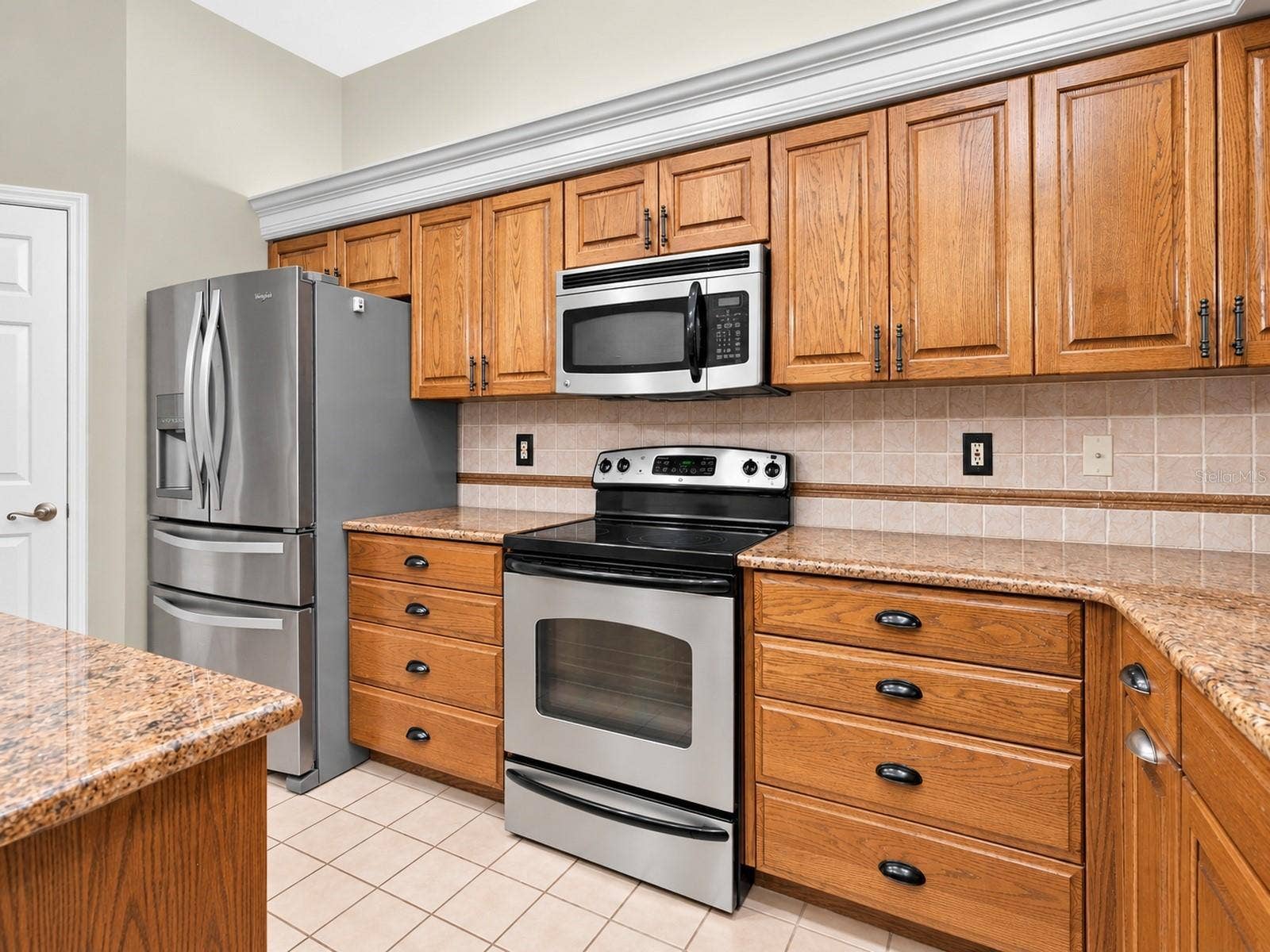 8732 SPRING COURT, Leesburg, FL 34788 Kitchen features oak cabinetry, center island, granite countertops, and stainless steel appliances.