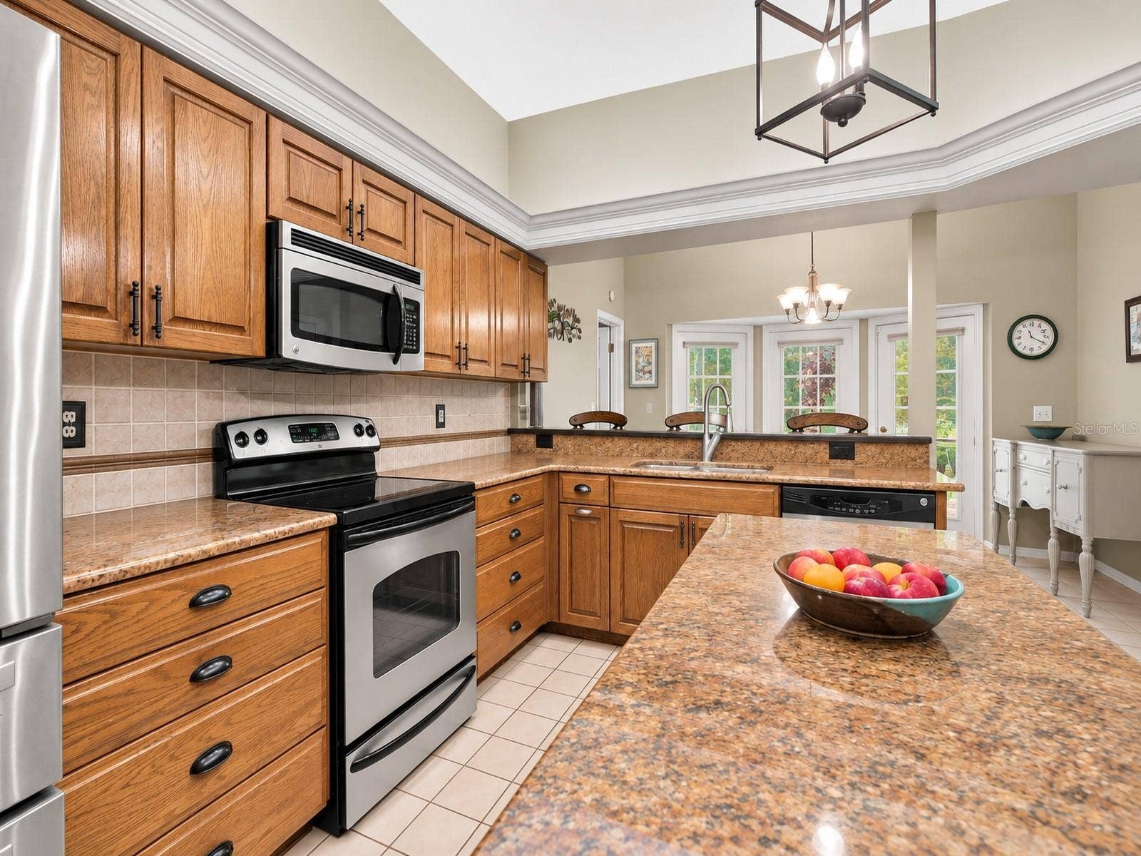 8732 SPRING COURT, Leesburg, FL 34788 Kitchen features oak cabinetry, center island, granite countertops, and stainless steel appliances.