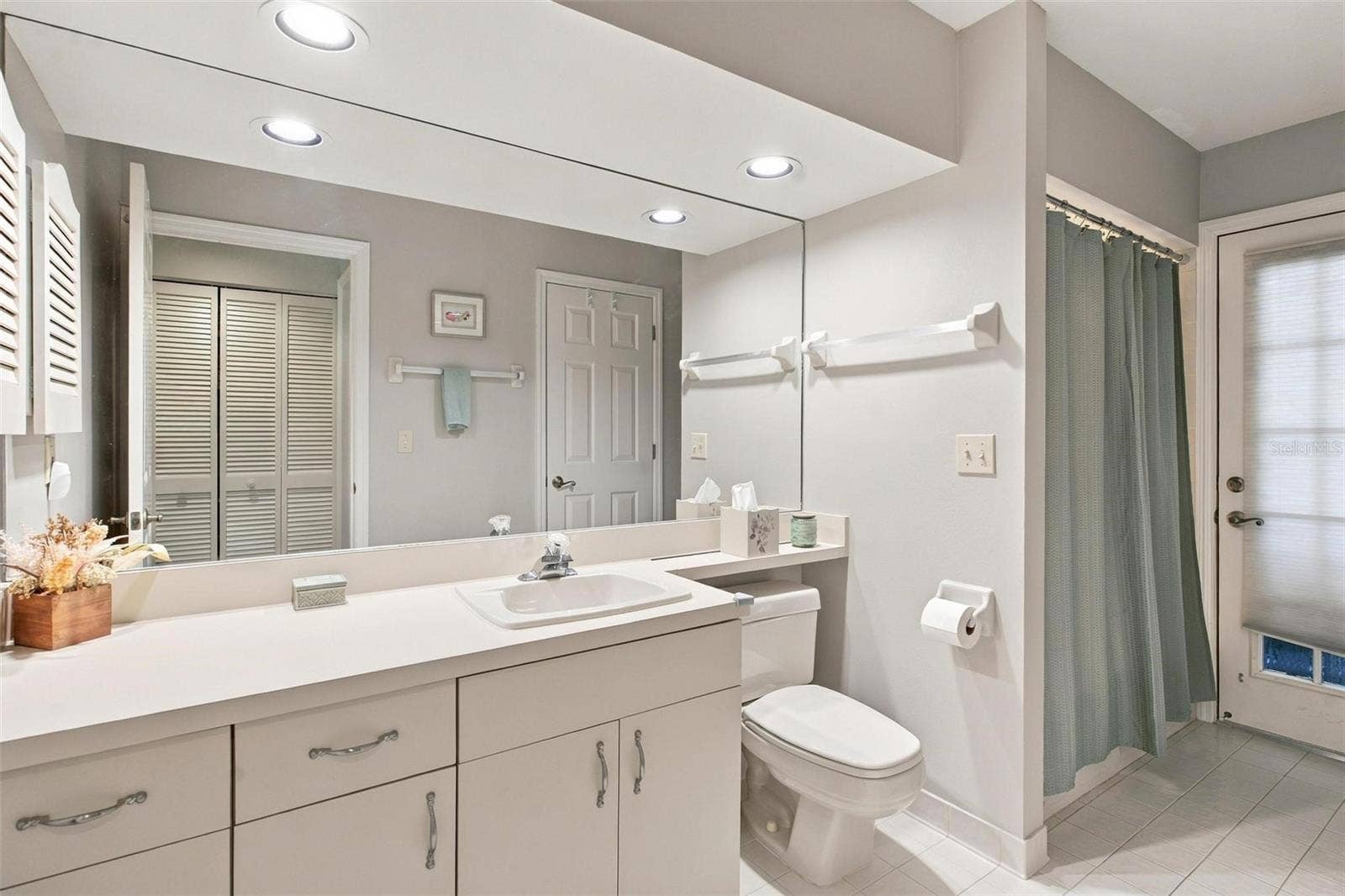 8732 SPRING COURT, Leesburg, FL 34788 Guest bath features shower/tub combo, door leading to screened enclosed lanai, and access to 3rd bedroom.