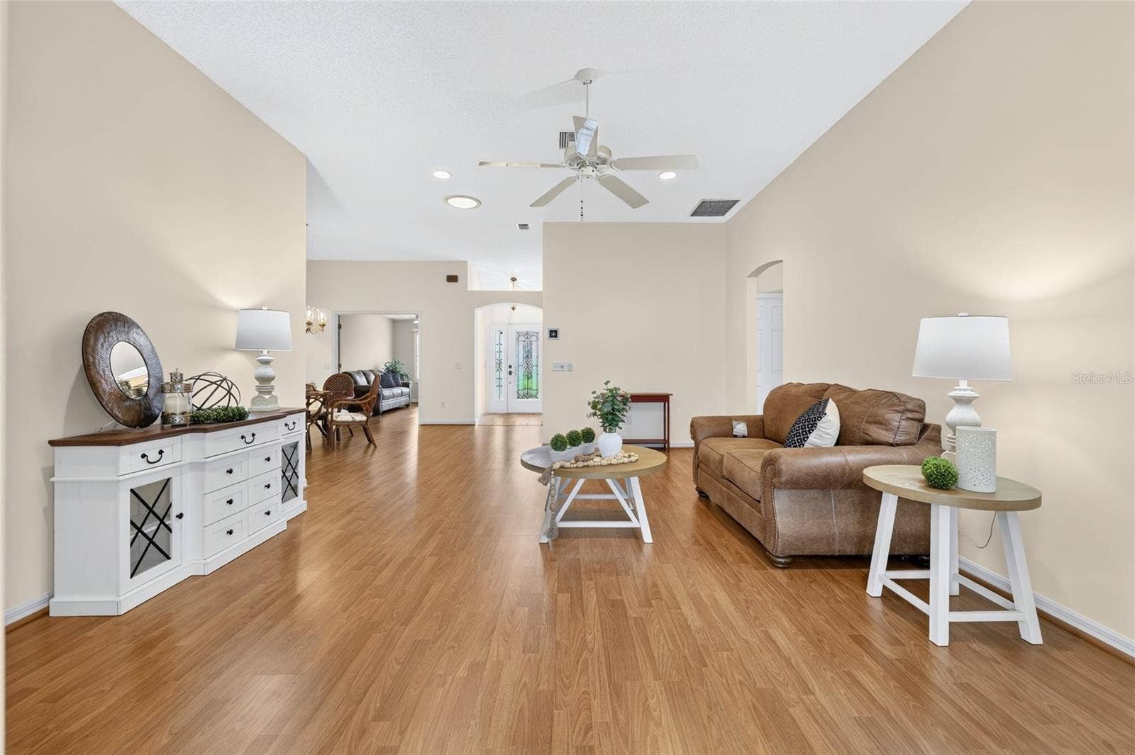 3064 BURBANK LANE, The Villages, FL 32162 Expansive living area showcasing an open floor plan, vaulted ceilings, abundant wall space, and a seamless connection to the dining area and foyer.