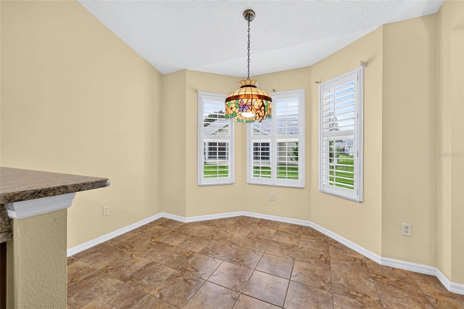 3064 BURBANK LANE, The Villages, FL 32162 Charming breakfast nook featuring a bay-style window arrangement with plantation shutters, decorative pendant lighting, and easy access to the kitchen.
