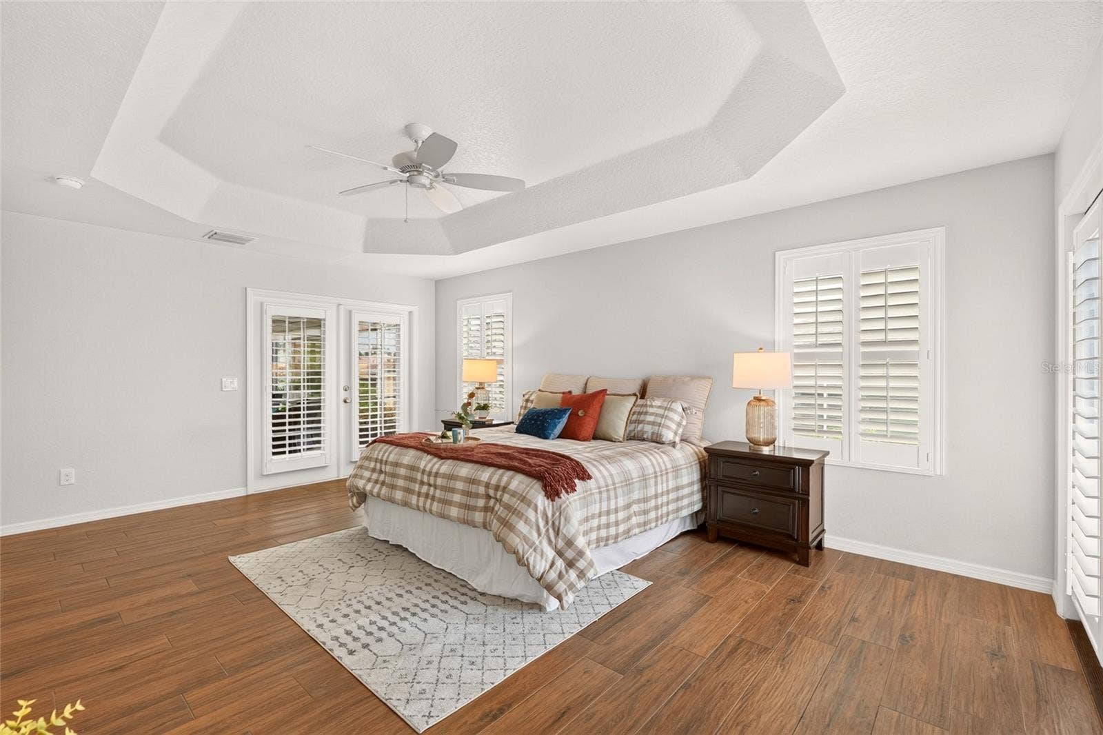 2454 MORNING DOVE LANE, The Villages, FL 32162 An elegant TRAY CEILING and beautiful natural light enhance this inviting PRIMARY SUITE, with French doors opening to the enclosed lanai for a peaceful place to unwind.
