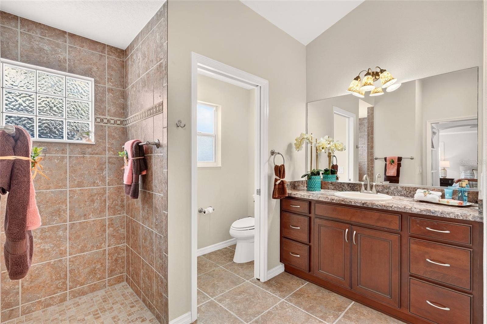 2454 MORNING DOVE LANE, The Villages, FL 32162 The PRIMARY BATH offers DUAL VANITIES, generous cabinet storage, and a spacious tiled ROMAN SHOWER for a relaxing start to your day!