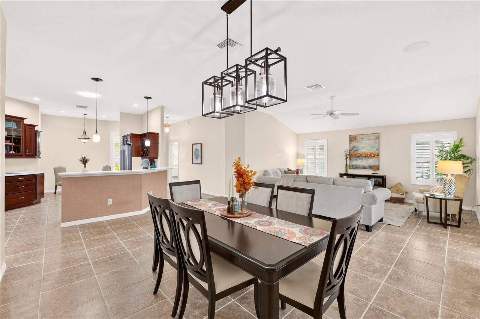 2454 MORNING DOVE LANE, The Villages, FL 32162 Inviting dining area with a stylish chandelier flows seamlessly into the spacious living room and kitchenperfect for entertaining or everyday relaxation.