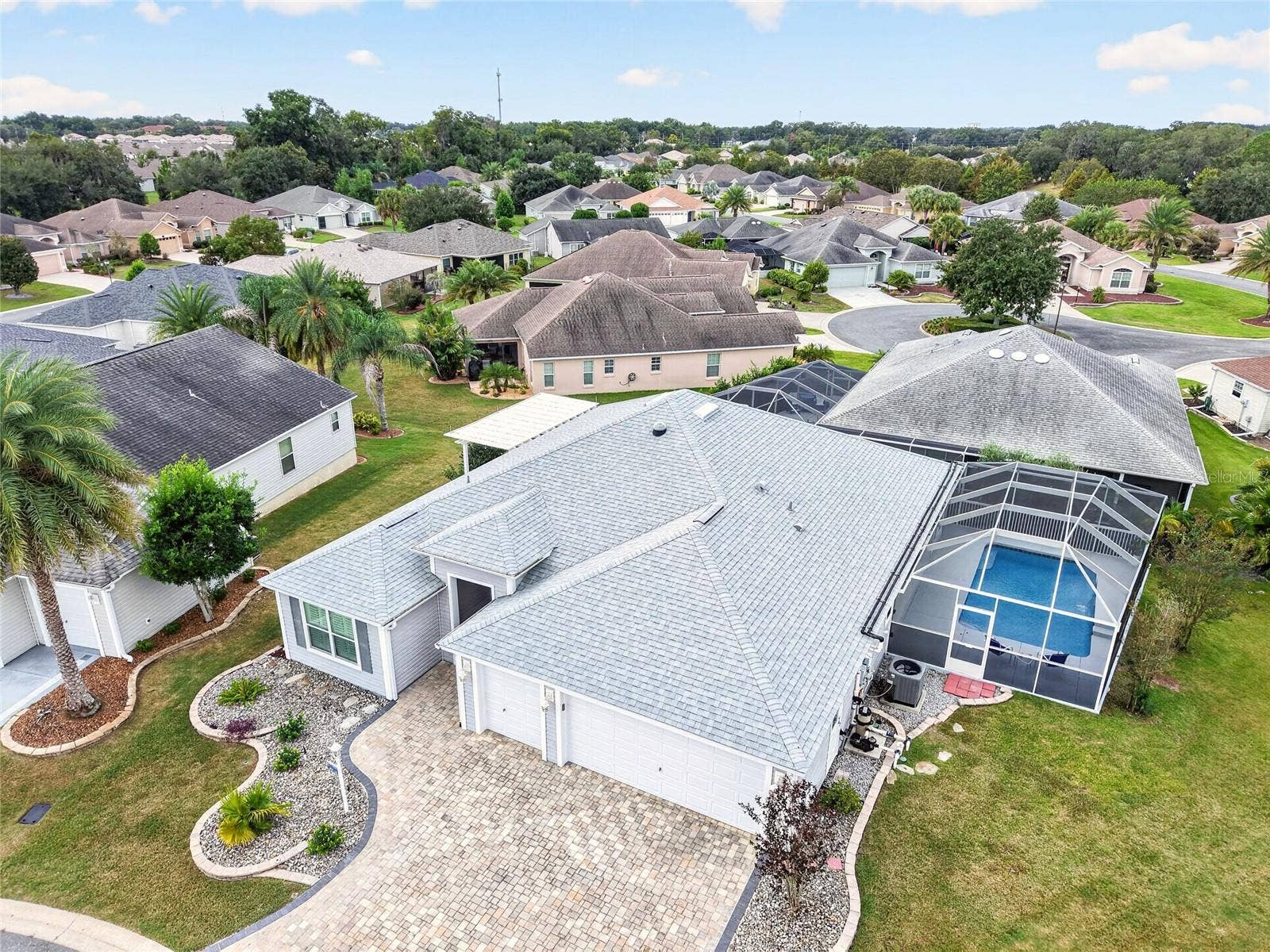 2454 MORNING DOVE LANE, The Villages, FL 32162 This aerial view showcases the screened pool retreat, pergola patio, and beautifully landscaped grounds, offering inviting spaces to relax and entertain.