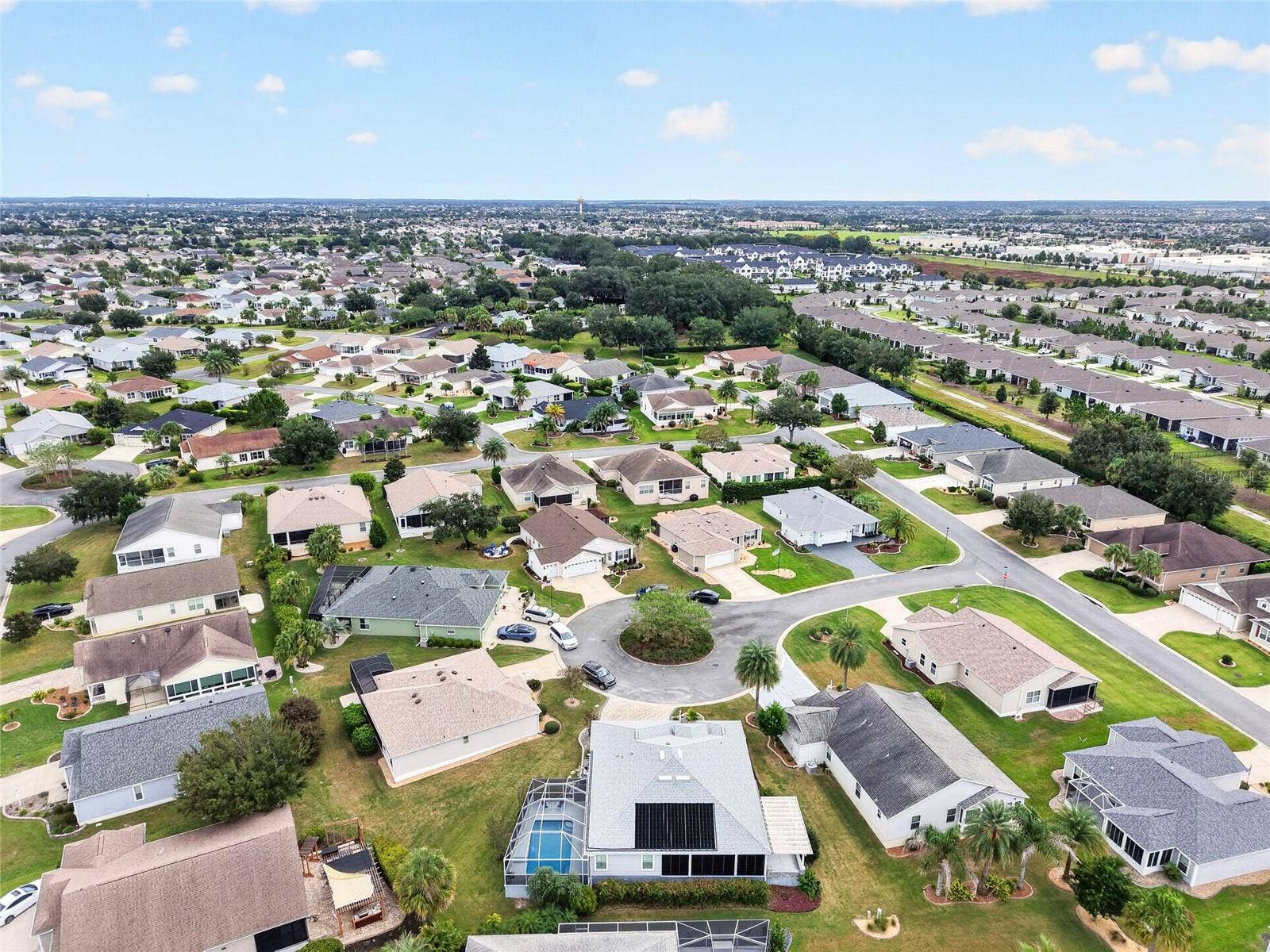 2454 MORNING DOVE LANE, The Villages, FL 32162 This elevated view from the rear showcases the SCREENED POOL RETREAT and spacious backyard, framed by a sweeping panorama of the surrounding neighborhood.