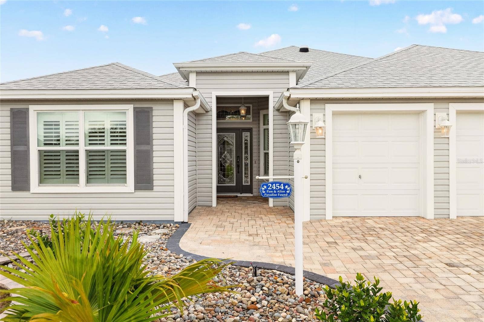 2454 MORNING DOVE LANE, The Villages, FL 32162 Beautiful landscaping, a paver driveway, and a welcoming covered entry create inviting curb appeal for this charming Florida home.