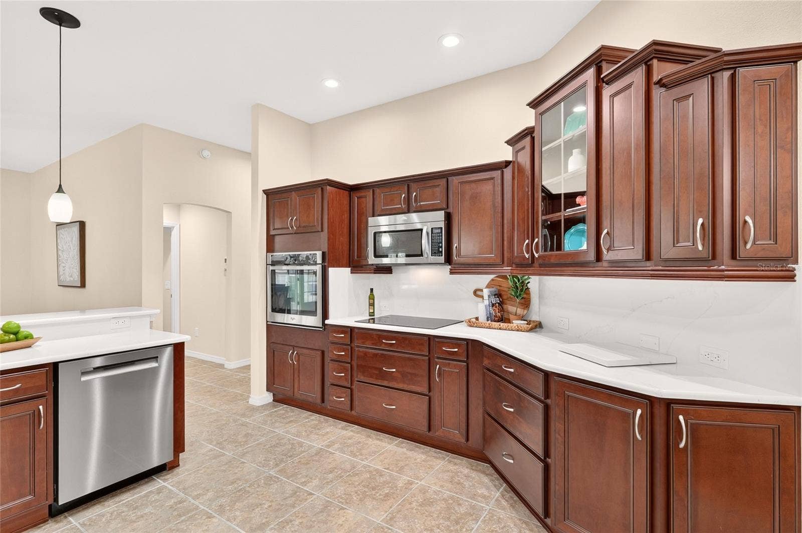 2454 MORNING DOVE LANE, The Villages, FL 32162 Beautiful CROWNED CABINETRY, QUARTZ COUNTERTOPS, and STAINLESS STEEL APPLIANCES create an inviting kitchen with a spacious breakfast bar for casual dining and conversation.