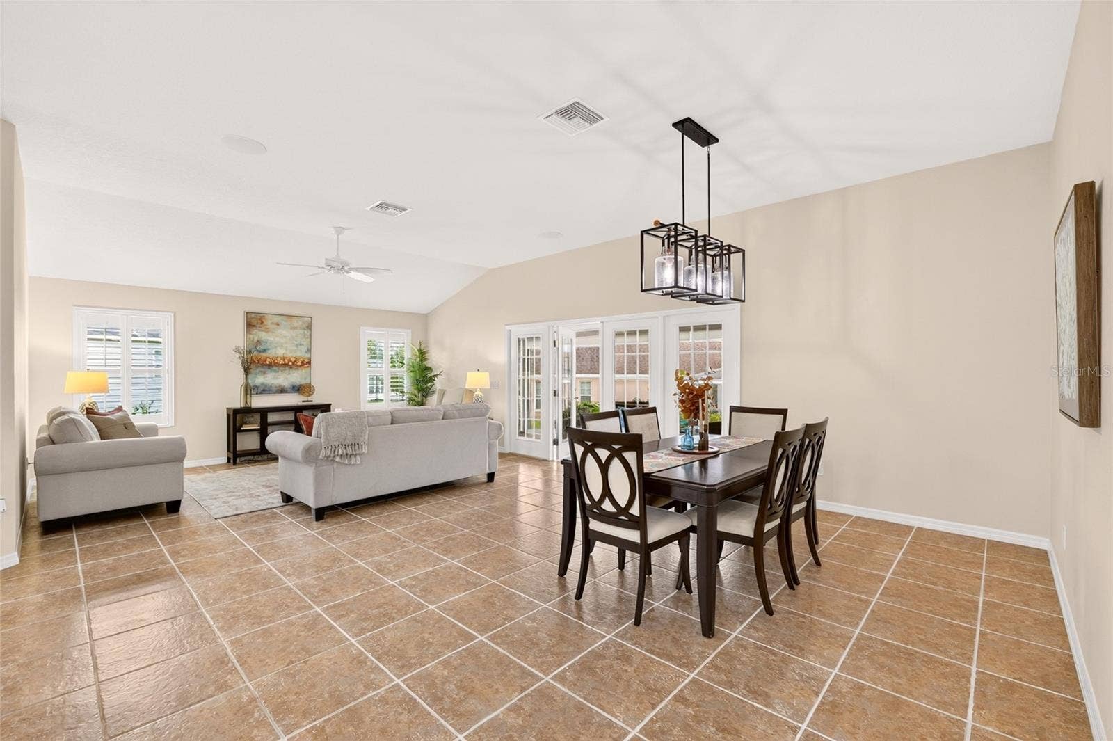2454 MORNING DOVE LANE, The Villages, FL 32162 VOLUME CEILINGS, beautiful TILE FLOORING, and PLANTATION SHUTTERS enhance the open living and dining area, with French doors leading to the enclosed lanai for effortless entertaining.