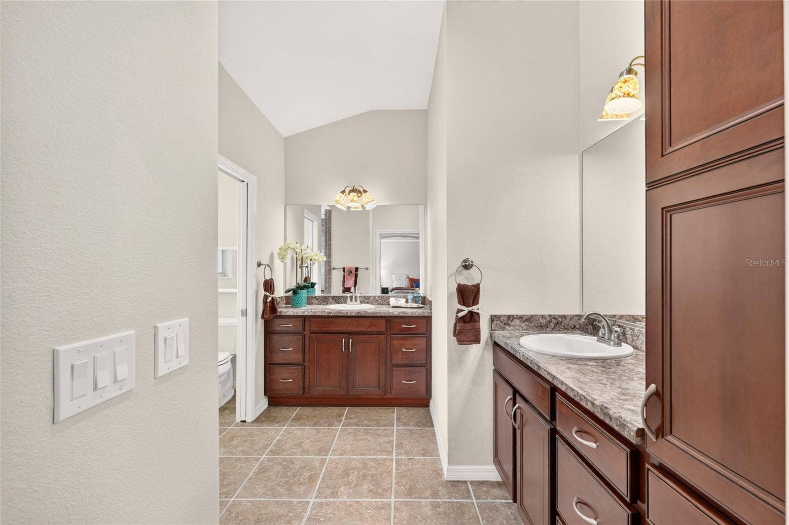 2454 MORNING DOVE LANE, The Villages, FL 32162 The spacious PRIMARY BATH combines DUAL VANITIES, rich cabinetry, and a tiled ROMAN SHOWER, with a separate water closet for added privacy.