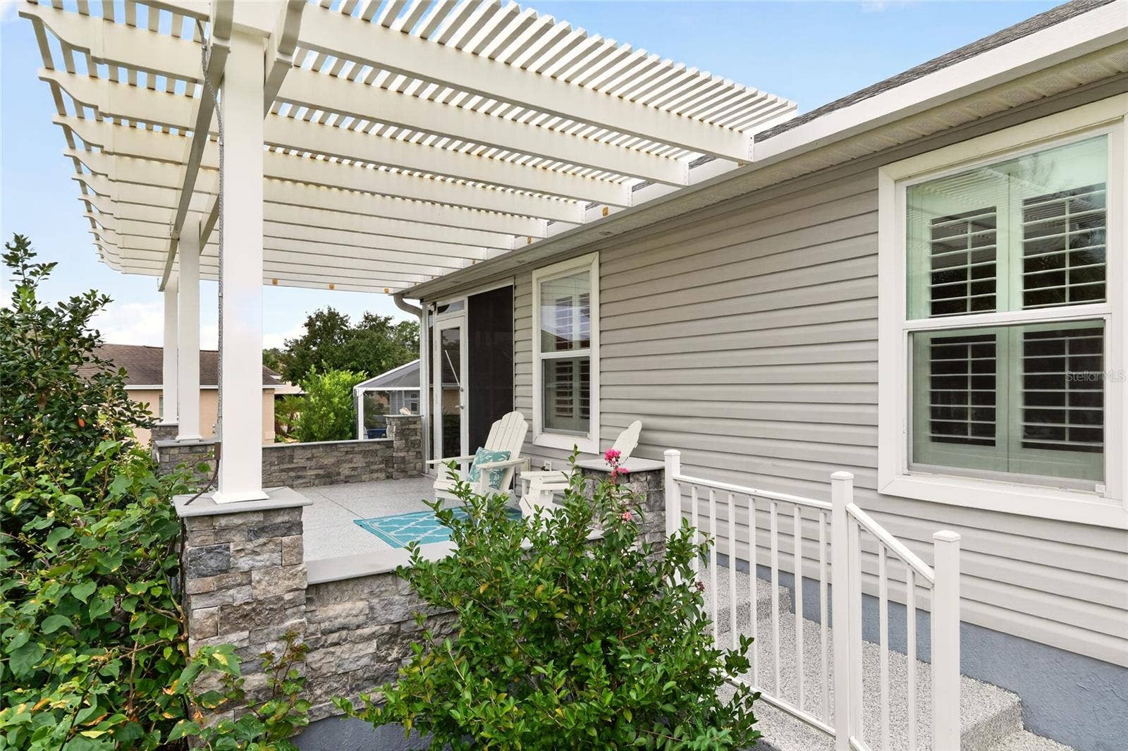 2454 MORNING DOVE LANE, The Villages, FL 32162 Unwind beneath the PERGOLA on this inviting patio, where decorative STONE ACCENTS and lush landscaping create a charming setting for outdoor dining and sunset conversations.