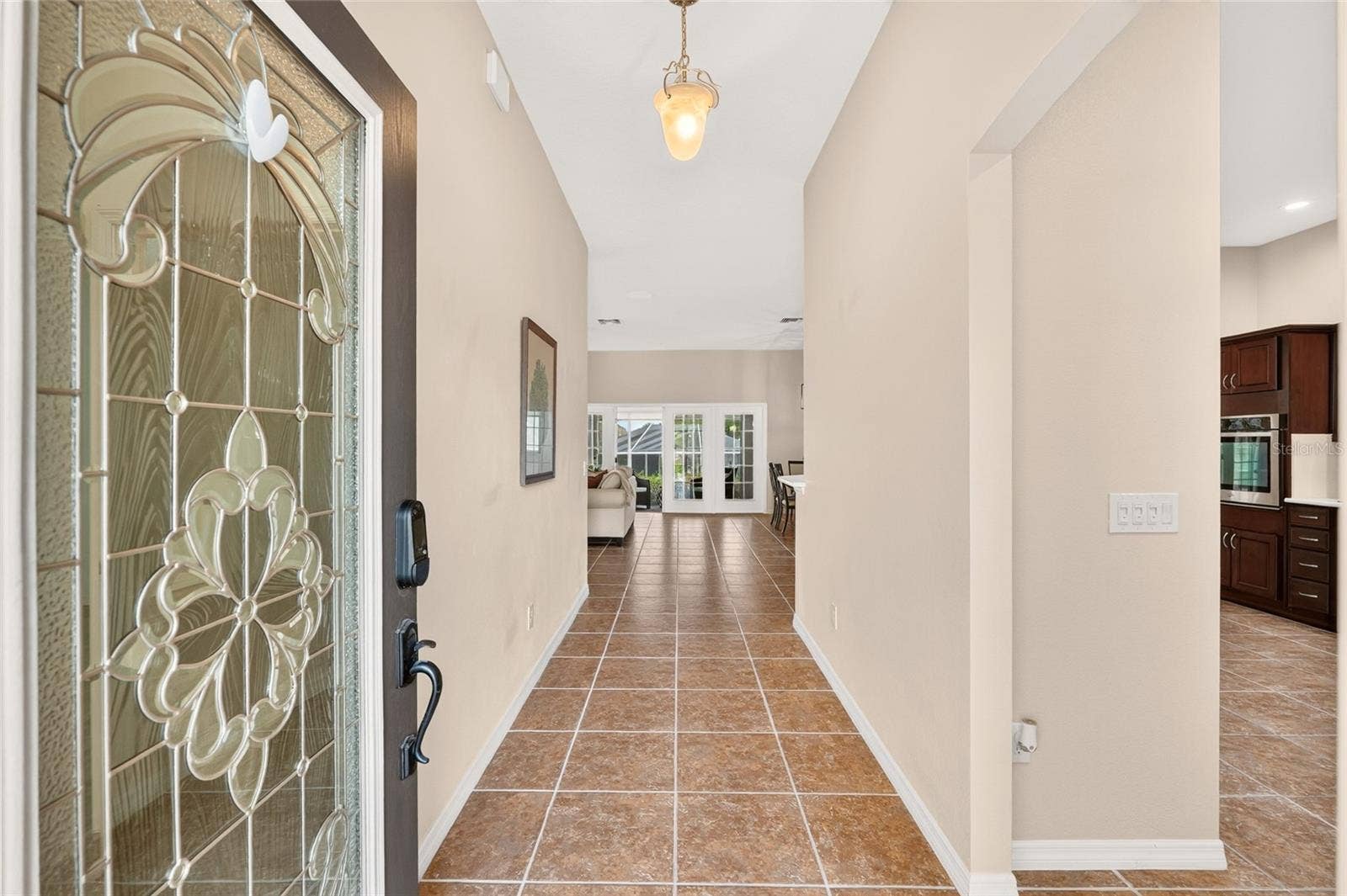 2454 MORNING DOVE LANE, The Villages, FL 32162 A decorative glass front door welcomes you into a bright foyer with tile flooring and an inviting view into the living spaces beyond.