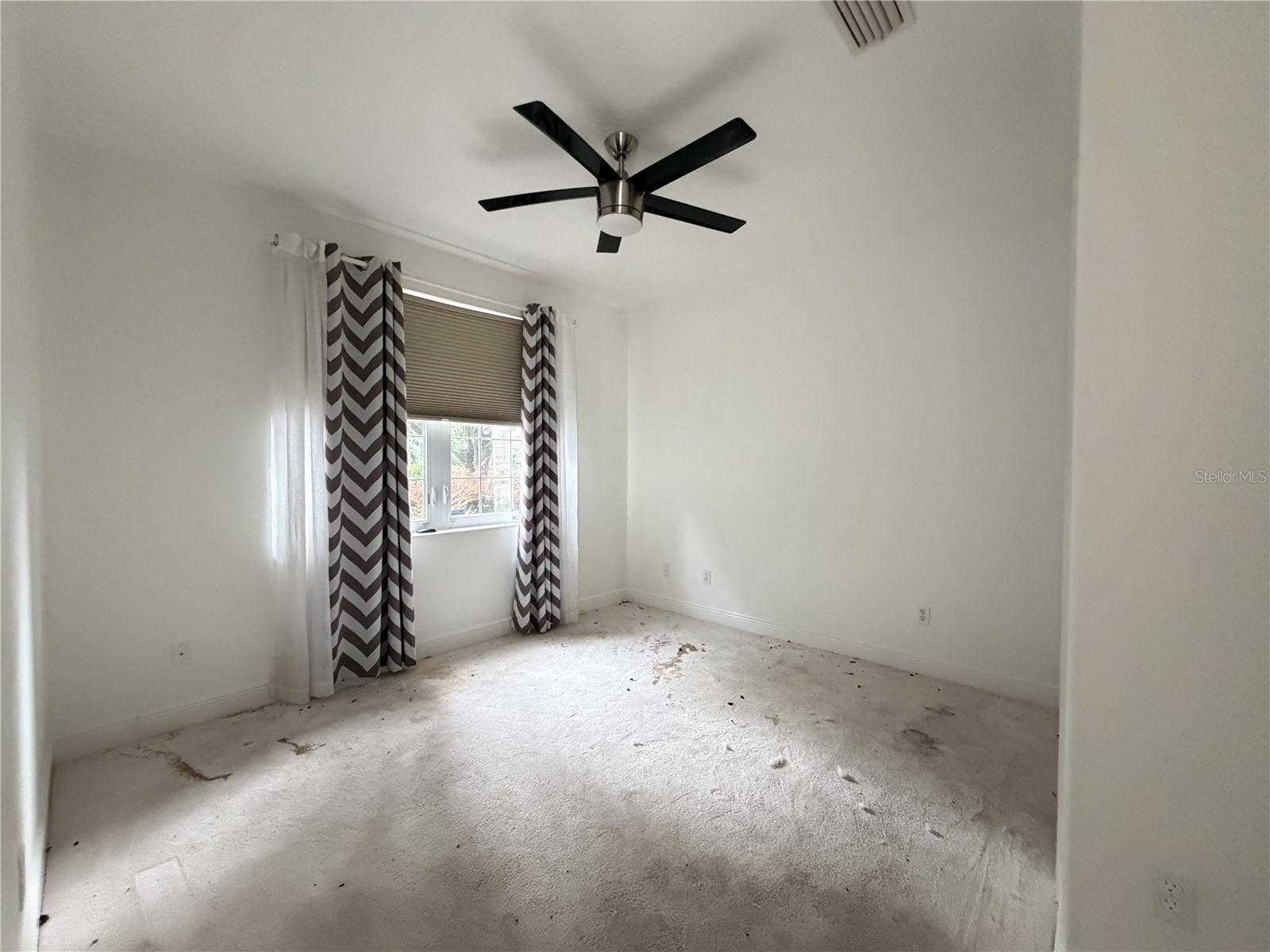 39539 HARBOR HILLS BOULEVARD, Lady Lake, FL 32159 Secondary bedroom with ceiling fan, window, and heavily stained carpet.