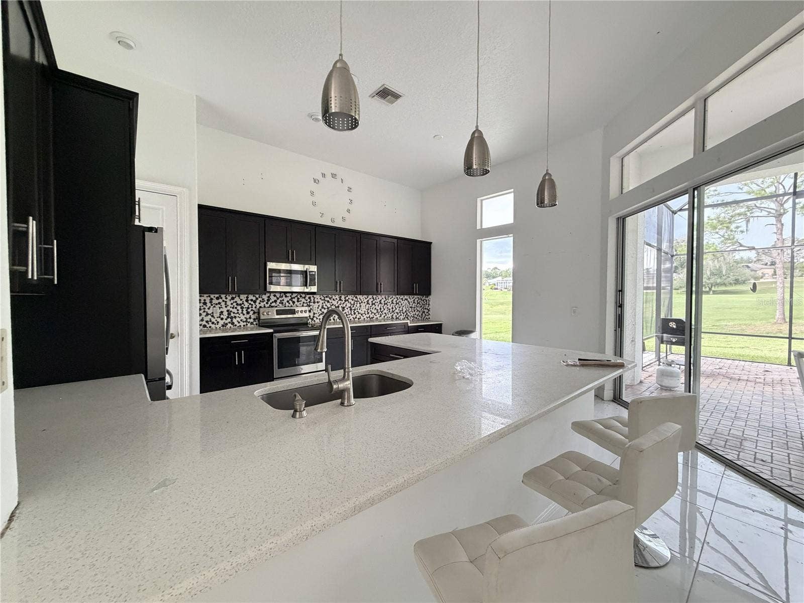 39539 HARBOR HILLS BOULEVARD, Lady Lake, FL 32159 Kitchen with extended breakfast bar, pendant lights, and lanai access.