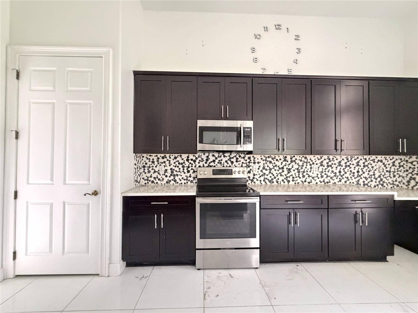 39539 HARBOR HILLS BOULEVARD, Lady Lake, FL 32159 Electric range, microwave, patterned backsplash, and cabinet storage.